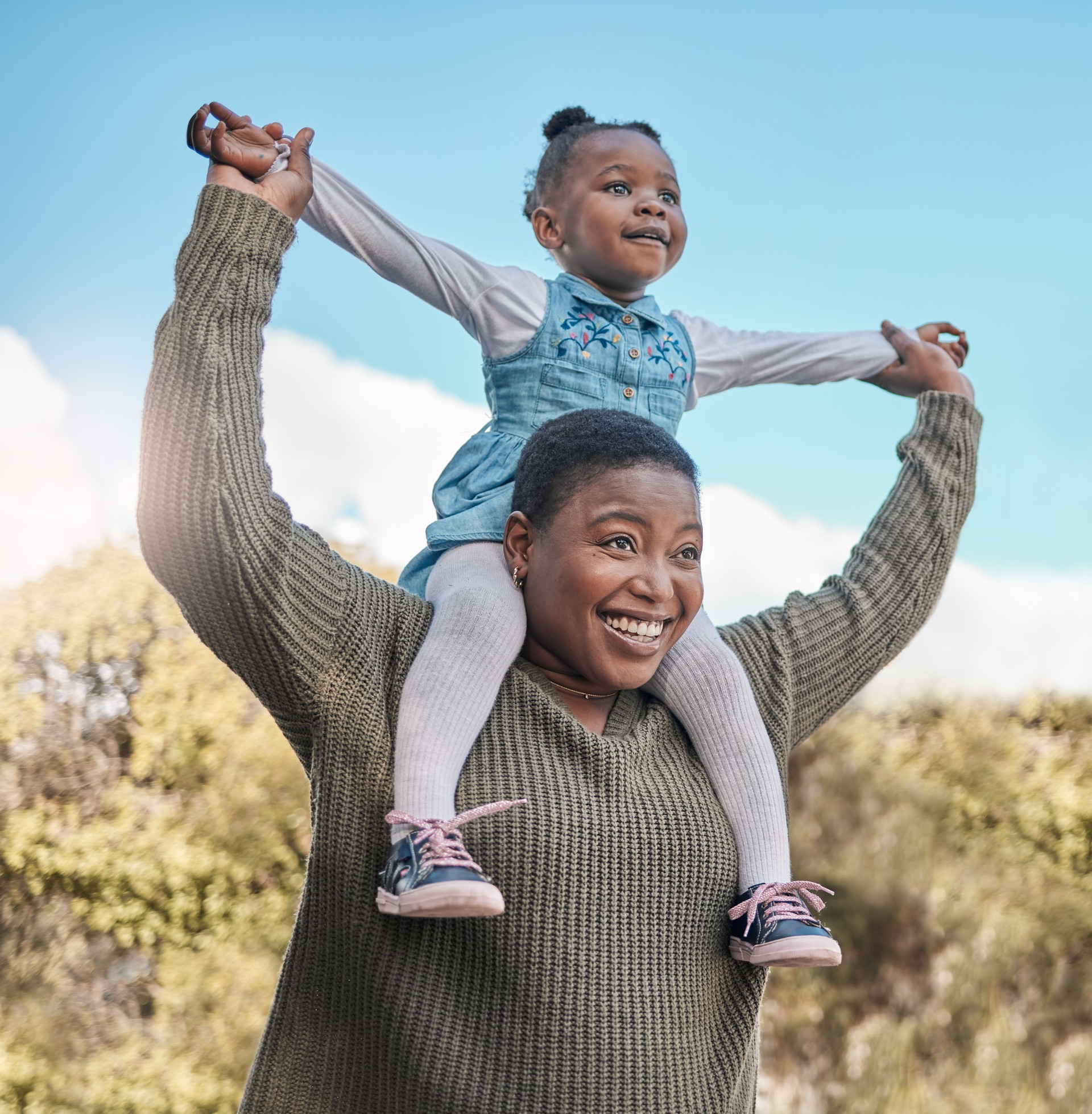 Shot of a mother carrying her daughter on her shoulders outdoors Shot of a mother carrying her daughter on her shoulders outdoors
